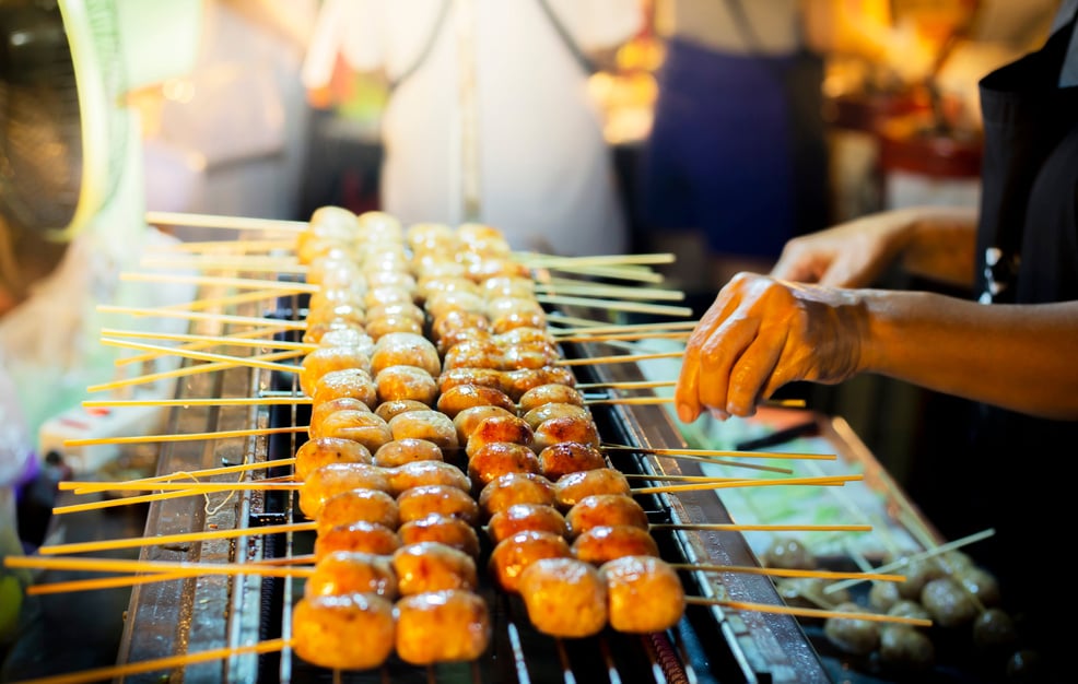 Woman is hand holding grill Thai Isaan Sausage.