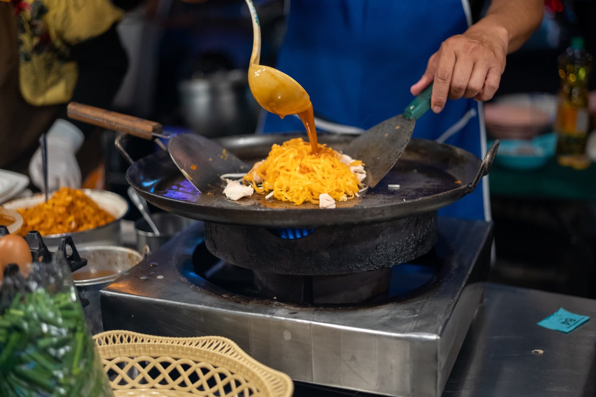 Thai street food vendor preparing Thai street food pad thai at market stall